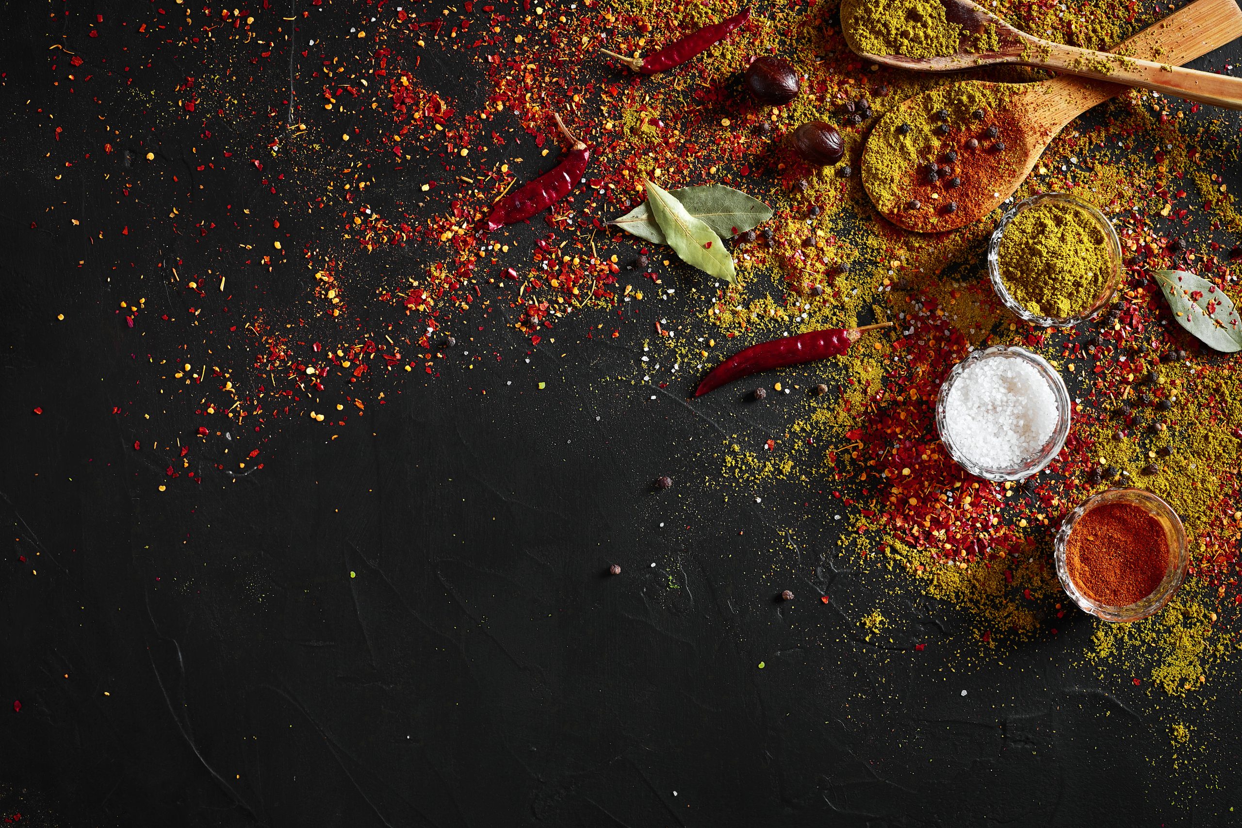Assorted spices on dark black background. Seasonings for food. Curry, paprika, pepper, cardamom, turmeric. Top view